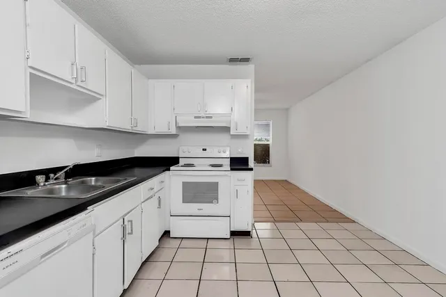a kitchen with white cabinets a sink and white appliances
