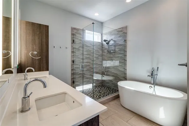 a bathroom with a granite countertop sink a bathtub a mirror and shower