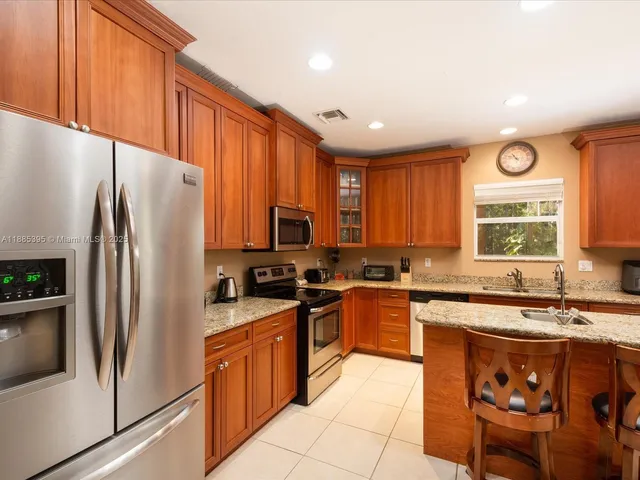 a kitchen with stainless steel appliances granite countertop a stove top oven a sink and a refrigerator