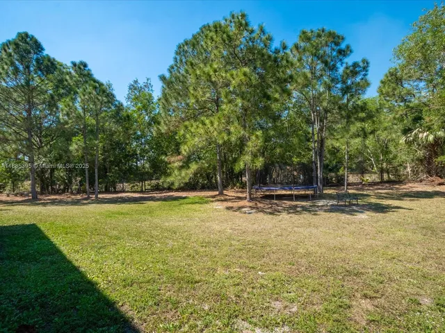a view of a big house with a big yard and large trees
