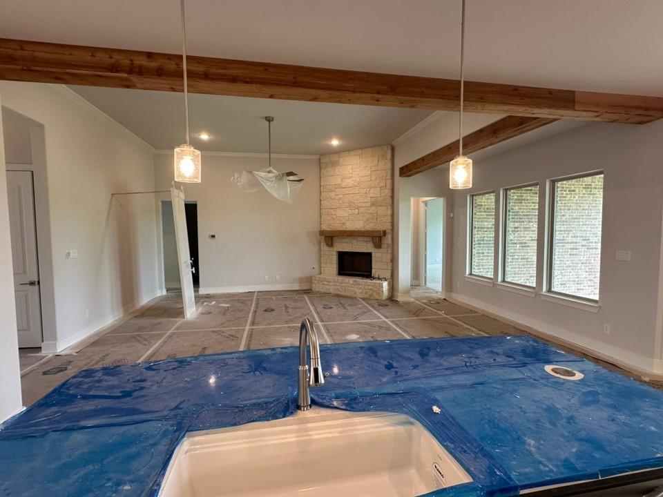 410 Cobb Road Leonard, TX 75452 - Photo 10 of 24 Open-concept living space featuring exposed wood beams, a stone-clad corner fireplace with a wood mantle, and multiple large windows