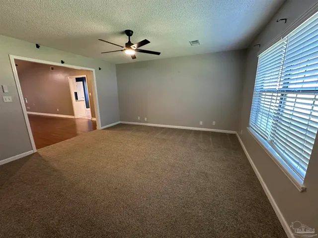 an empty room with windows and fan