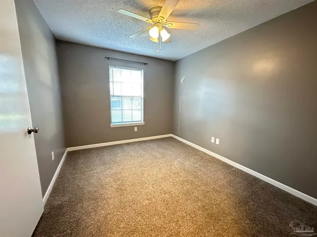 an empty room with a window and a fan