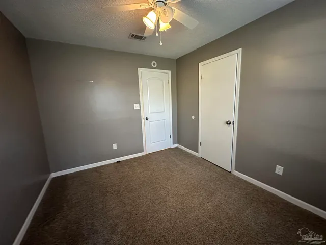 an empty room with a chandelier fan and windows