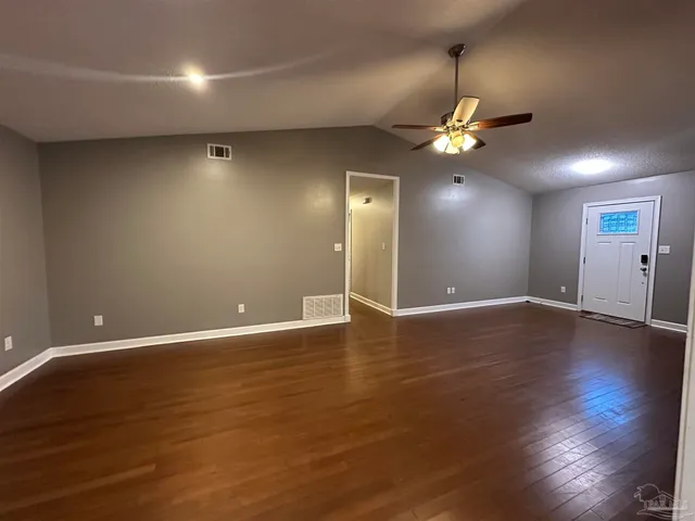 an empty room with wooden floor chandelier fan and windows