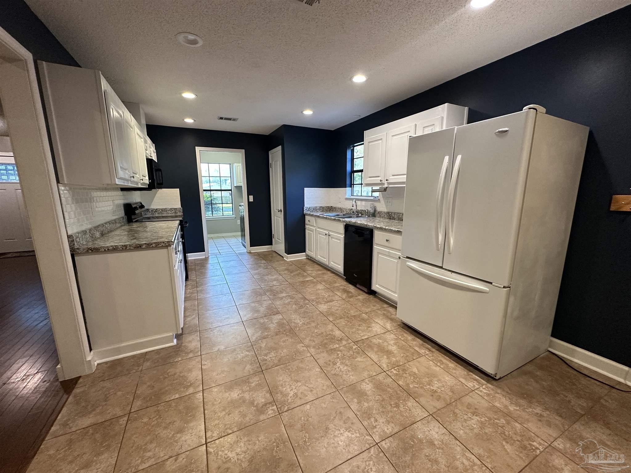 7720 Jansen Road Pensacola, FL 32526 - Photo 7 of 30 a kitchen with granite countertop a refrigerator a sink and white cabinets