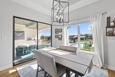 a dining room with wooden floor a chandelier a wooden table and chairs