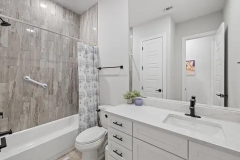 a bathroom with a granite countertop sink a toilet and a bathtub