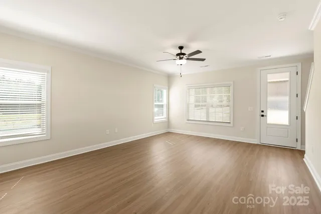 a view of an empty room with a window and wooden floor