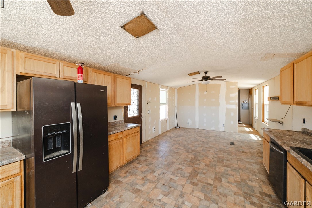 16435 South Wyatt Earp Road Yucca, AZ 86438 - Photo 7 of 57 Expansive open-concept living area featuring a functional kitchen layout with wood-finish cabinetry, a side-by-side refrigerator, and a built-in sink