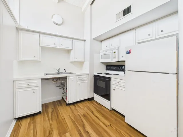 a kitchen with granite countertop white cabinets and white appliances