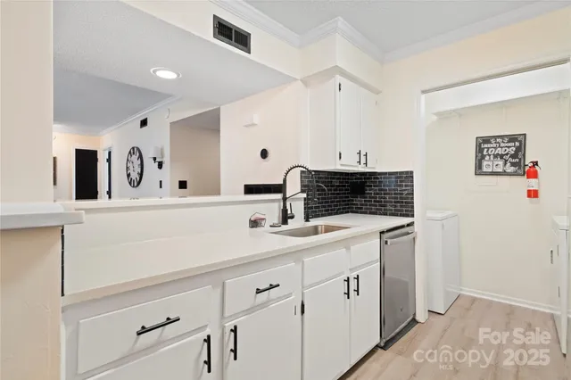a spacious white kitchen with a sink and dishwasher stove with wooden floor