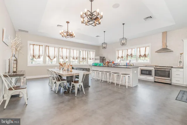 a dining room with kitchen island stainless steel appliances furniture a chandelier and a view of kitchen