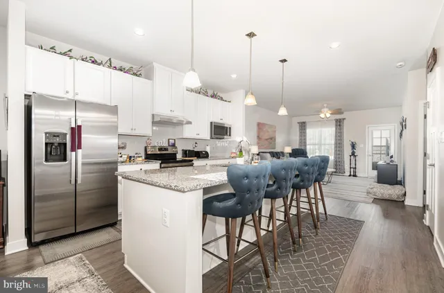 a kitchen with stainless steel appliances kitchen island a refrigerator and a wooden floor