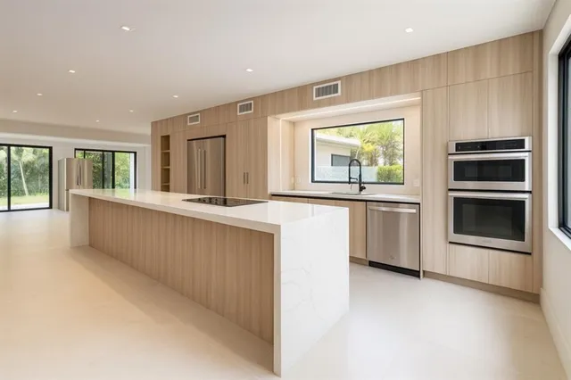 a large white kitchen with a sink and dishwasher a stove top oven with wooden floor