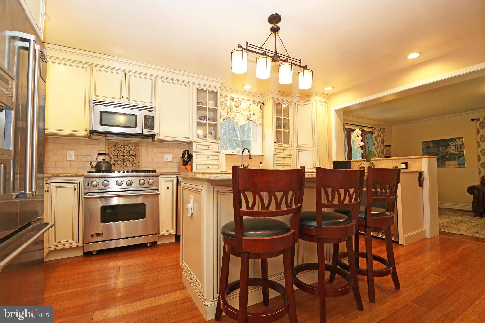 371 Southcroft Road Springfield, PA 19064 - Photo 7 of 42 a kitchen with stainless steel appliances kitchen island granite countertop a stove a sink a dining table and chairs with wooden floor