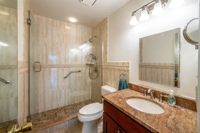 a bathroom with a granite countertop sink toilet a mirror and shower
