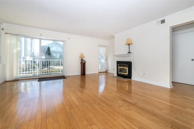 an empty room with wooden floor fireplace and windows