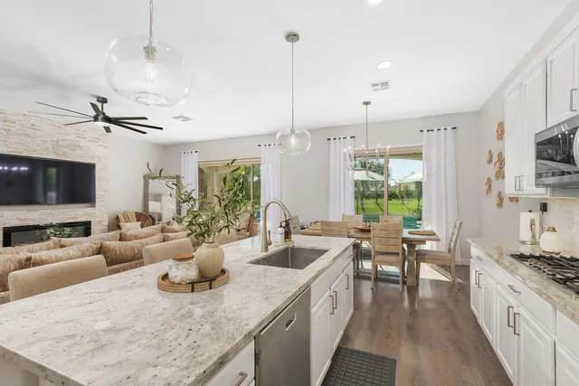 a large kitchen with kitchen island lots of counter space a sink appliances and a living room view