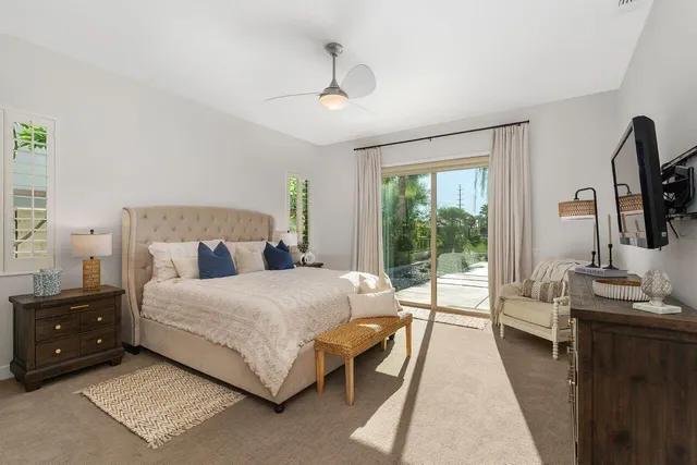 a bedroom with a bed a large window and flat screen tv