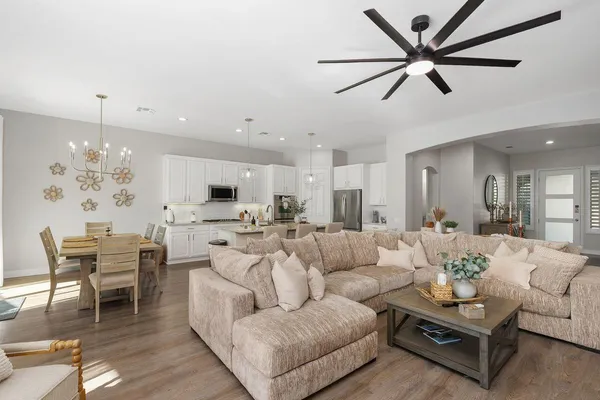 a living room with furniture kitchen view and a chandelier