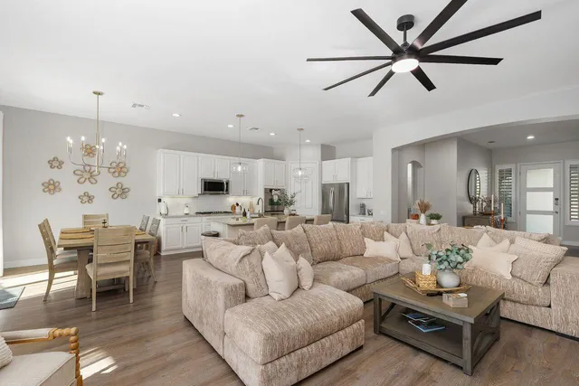a living room with furniture kitchen view and a chandelier