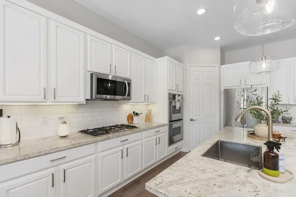 a kitchen with granite countertop a sink stainless steel appliances and white cabinets