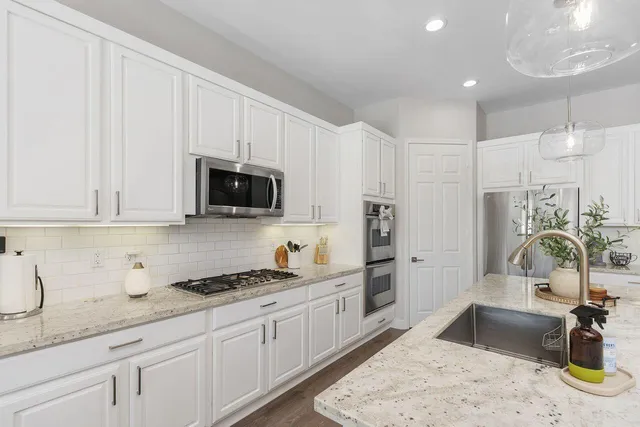 a kitchen with granite countertop a sink stainless steel appliances and white cabinets