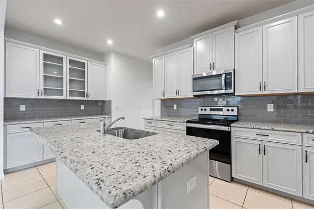 a kitchen with kitchen island granite countertop a sink stove and cabinets