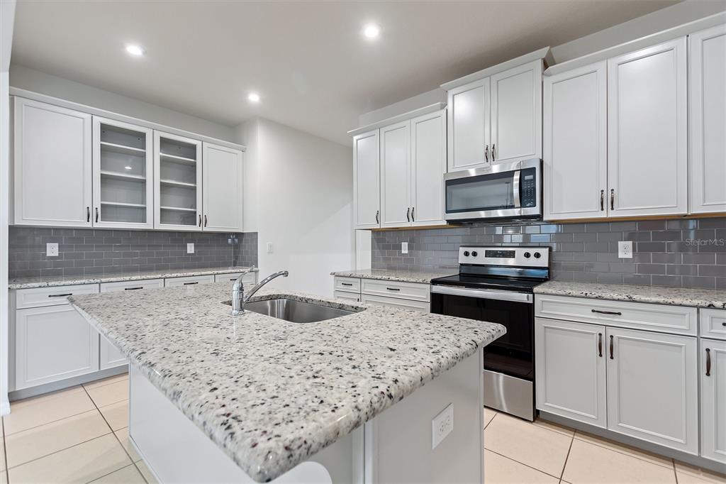 2500 Avian Loop Kissimmee, FL 34741 - Photo 17 of 35 a kitchen with kitchen island granite countertop a sink stove and cabinets