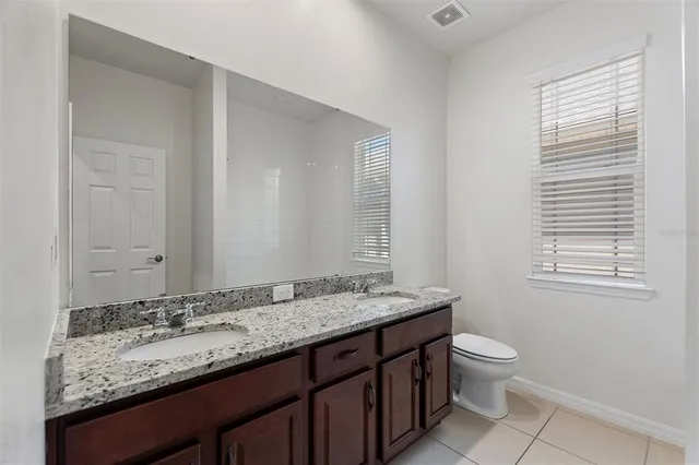 a bathroom with a granite countertop sink toilet and mirror