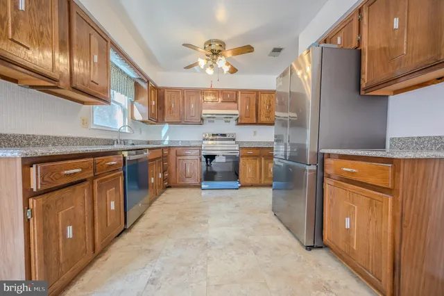 a kitchen with stainless steel appliances granite countertop a stove a sink dishwasher and a refrigerator