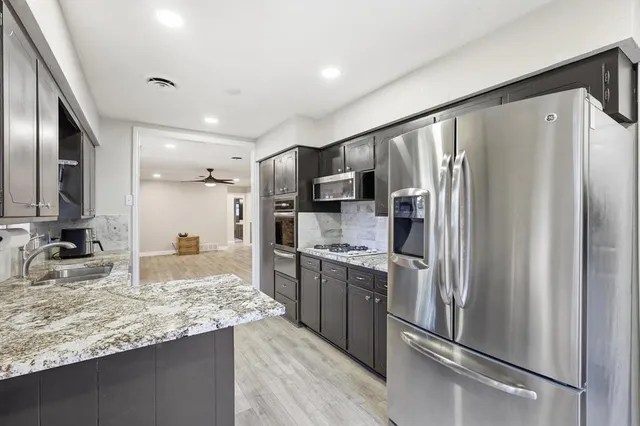 a kitchen with stainless steel appliances granite countertop a refrigerator and a sink