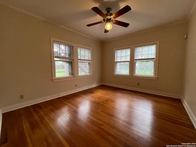 a view of an empty room with wooden floor and a window