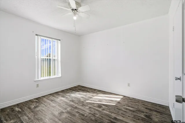an empty room with a window and ceiling fan