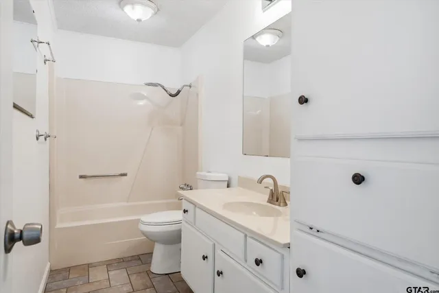 a bathroom with a granite countertop sink a toilet and shower