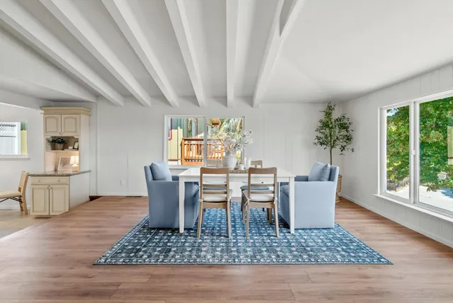 a dining room with wooden floor a chandelier fan a wooden table and chairs