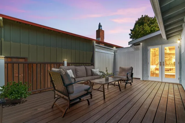 a backyard of a house with wooden floor barbeque oven table and chairs