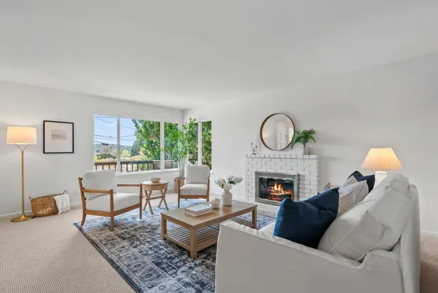 a living room with furniture a fireplace a rug and a window