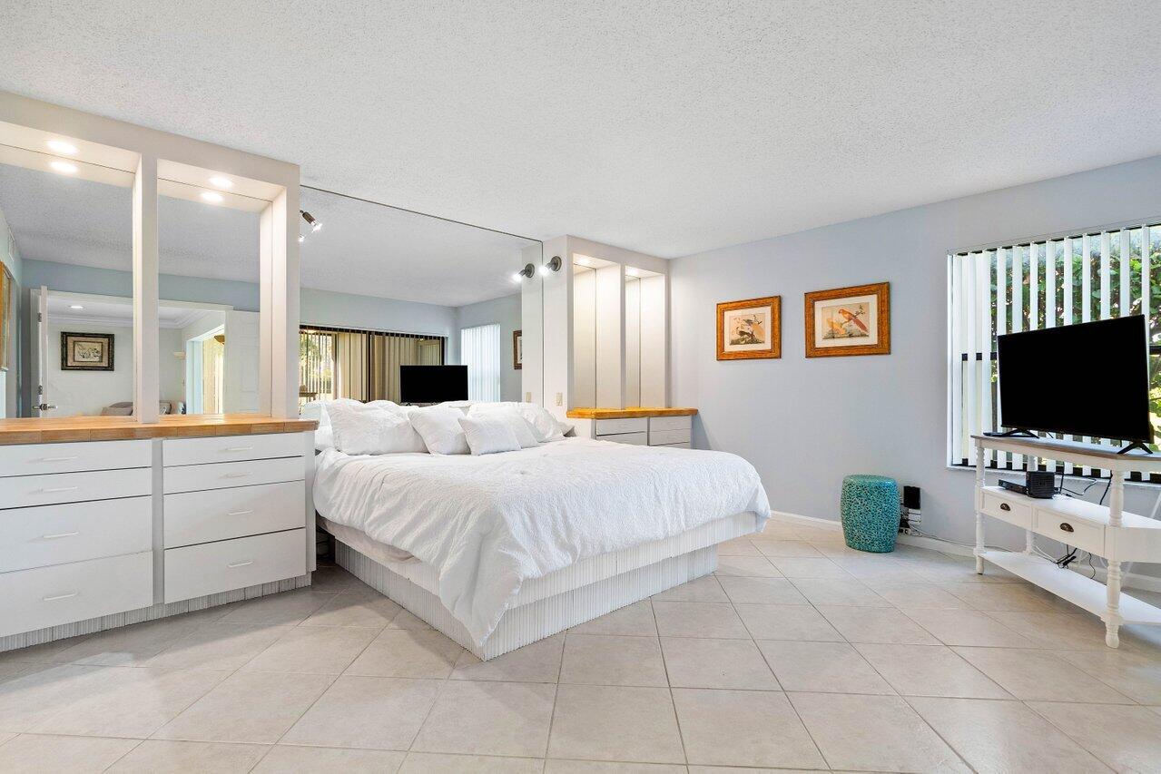 401 Clubhouse Circle, Unit 401A Jupiter, FL 33477 - Photo 14 of 34 a bedroom with a bed and a flat screen tv