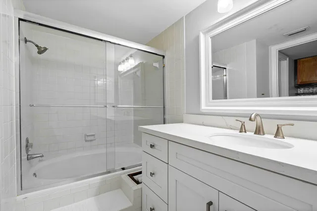 a bathroom with a shower sink vanity and mirror