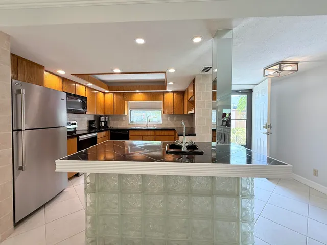 a kitchen with stainless steel appliances granite countertop a refrigerator and a sink