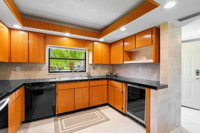 a kitchen with stainless steel appliances granite countertop a sink and a stove next to a window