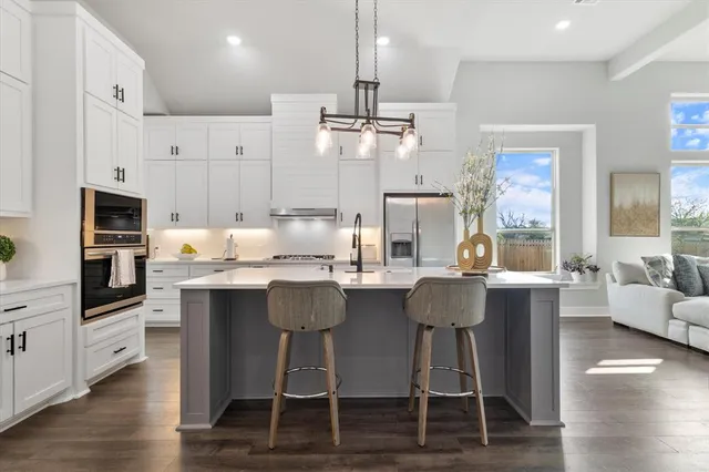 a kitchen with stainless steel appliances kitchen island granite countertop a dining table chairs and white cabinets