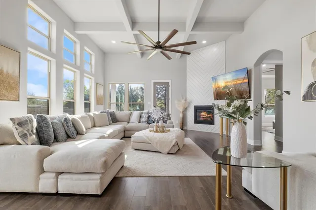 a living room with furniture a ceiling fan a flat screen tv and a large window