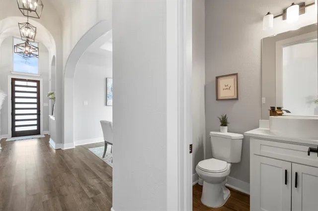 a bathroom with a toilet a sink and wooden floor