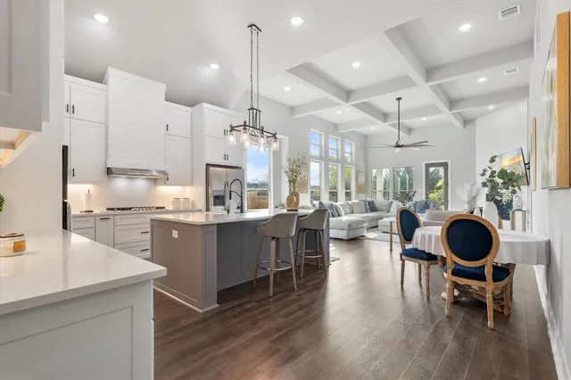 a kitchen with kitchen island granite countertop a large center island a sink a stove and a wooden floors