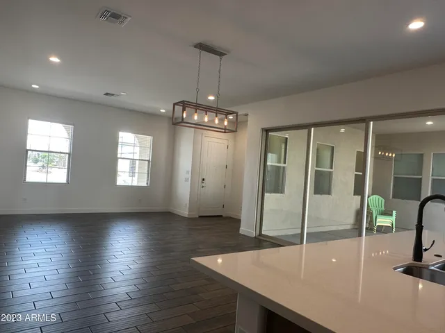 a dining room with wooden floor a chandelier a wooden table and chairs