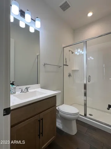 a bathroom with a sink a toilet a mirror and shower