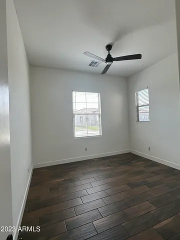an empty room with wooden floor fan and windows